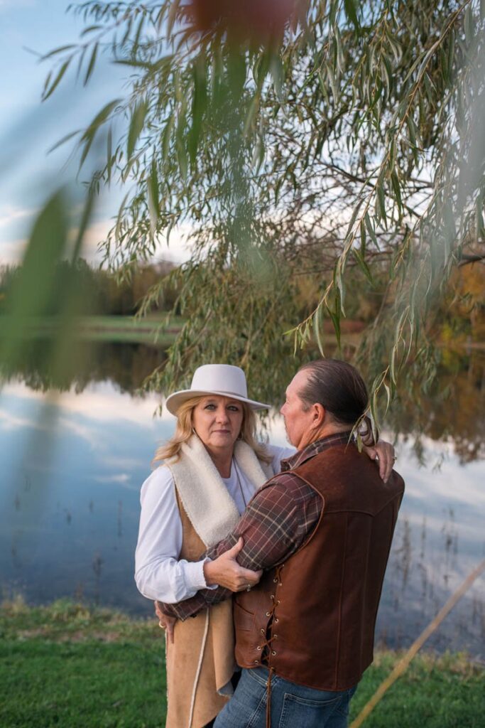 View of husband and wife through leaves of a willow tree at a couples photography session.