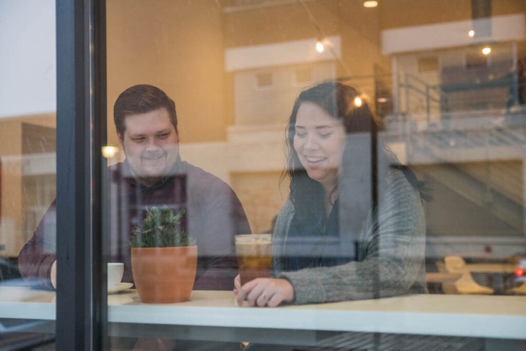 Couple enjoys drinking coffee together inside a coffee shop.