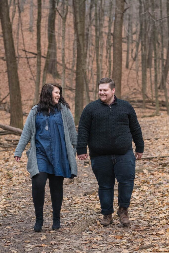Couple laughs while talking together and strolling through the forest.