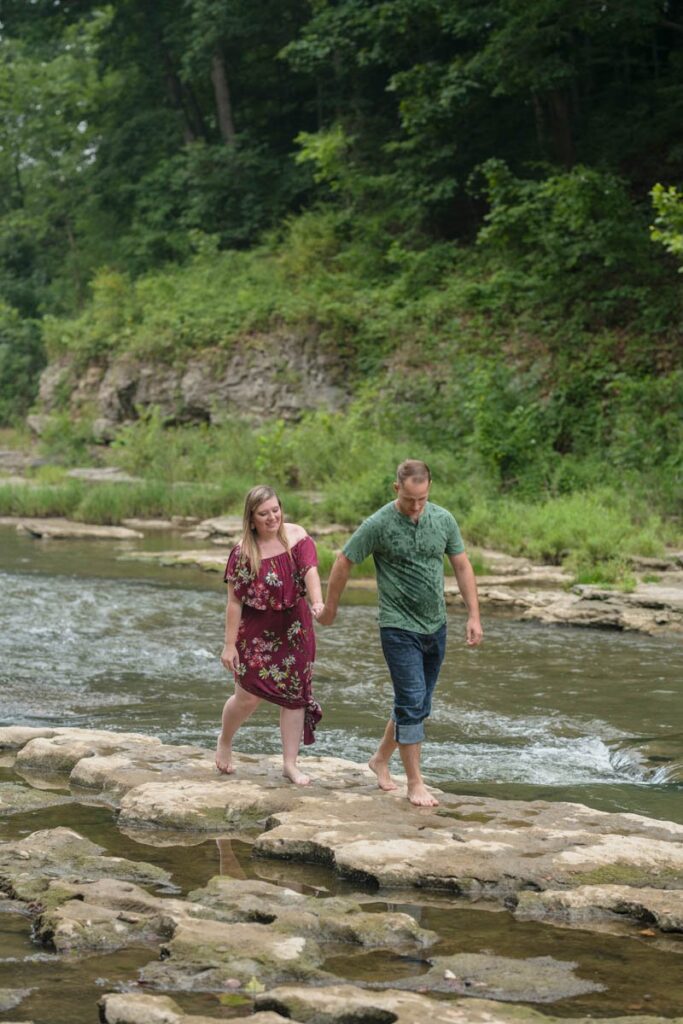 Happy couple is walking through shallow water holding hands.