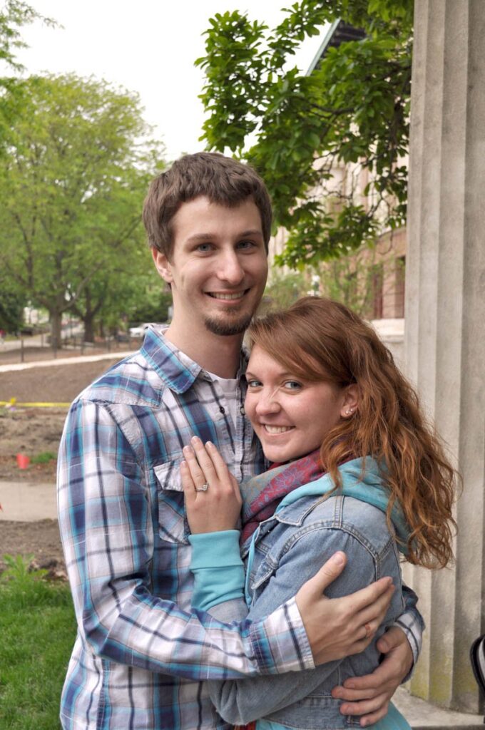 A newly engaged couple hugs and smiles.