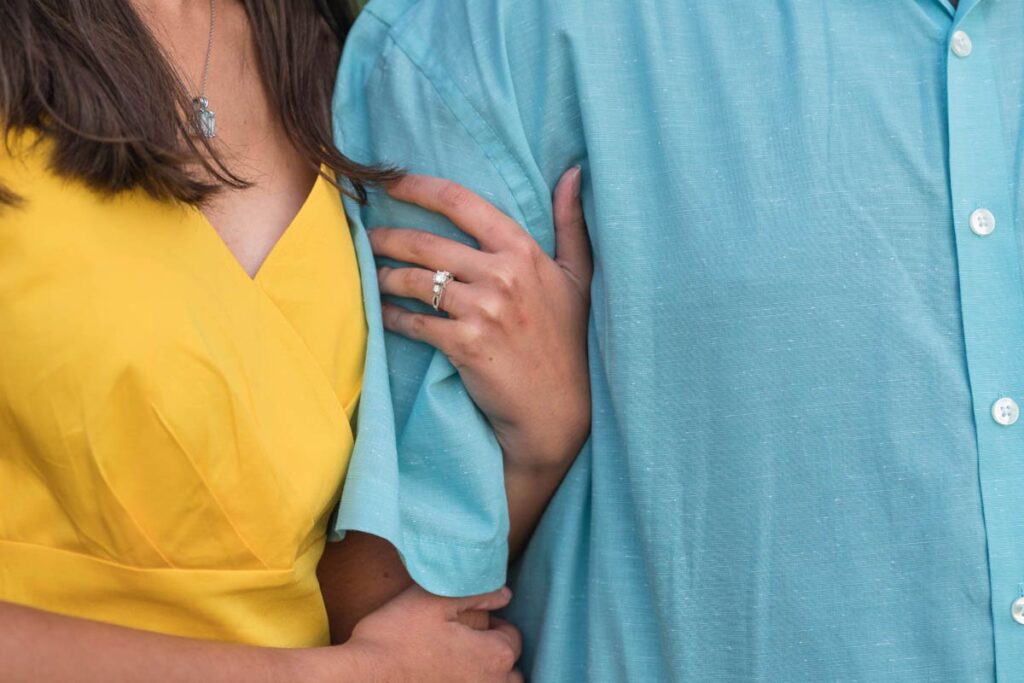 Woman in yellow dress holding onto the arm of her fiancé.