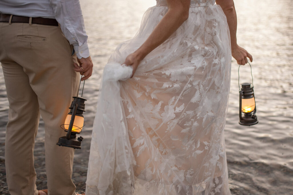 Bride and groom hold lanterns as they wade into the lake.