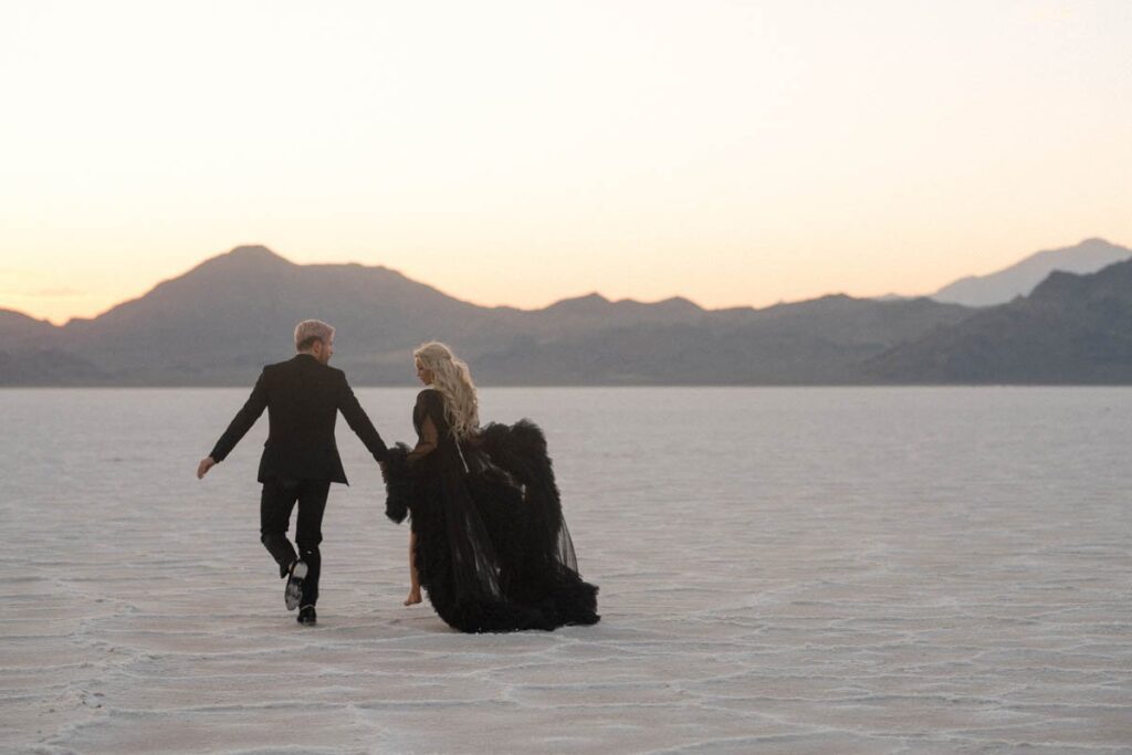 What's it mean to elope? It looks like a couple dressed in black celebrating and running towards the mountain range at sunset.