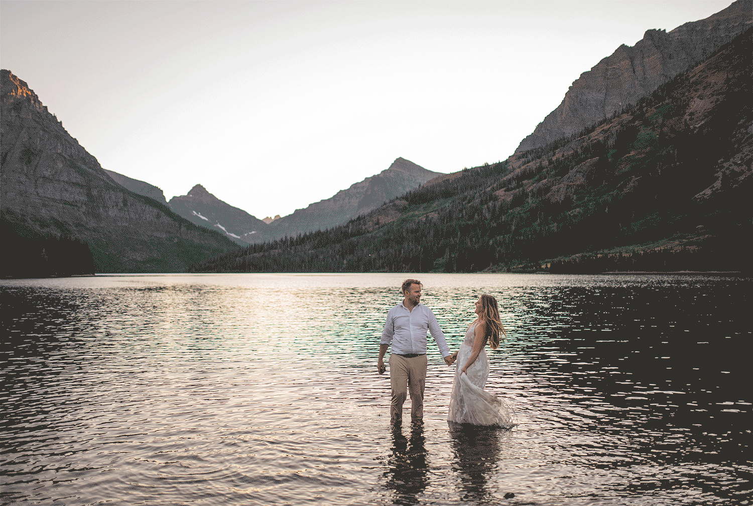 GIF of bride and groom playing together in lake among mountains.