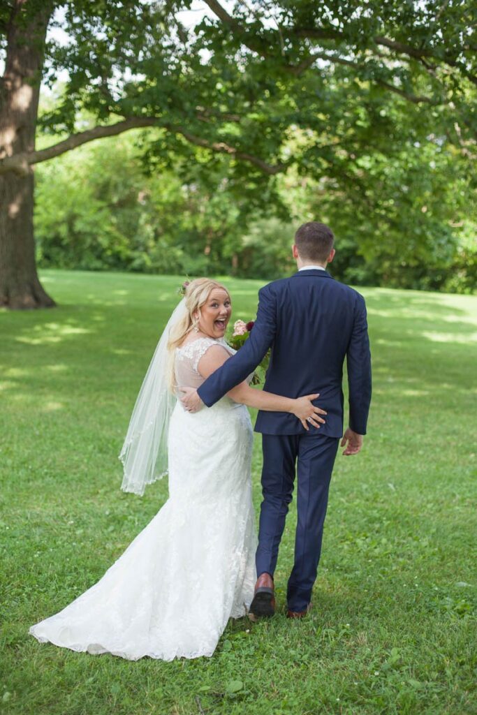 Bride looks over her shoulder and smiles as she rests her hands on the groom's butt.