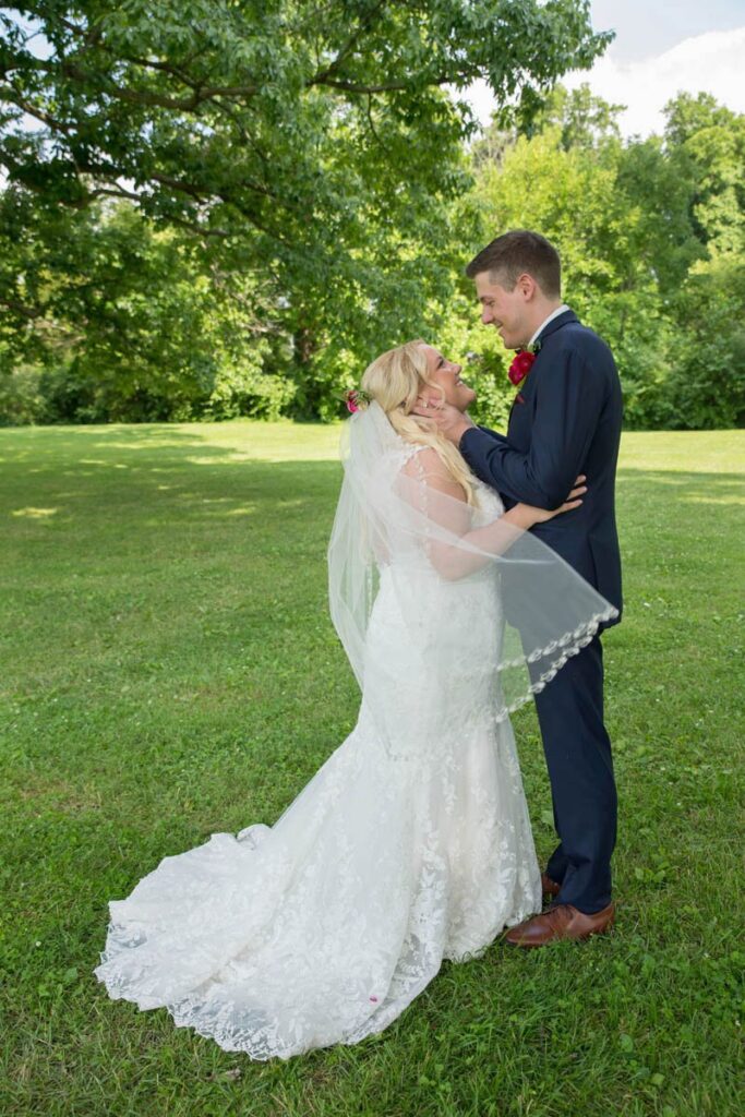 Bride's veil blows in the breeze as bride and groom hug.