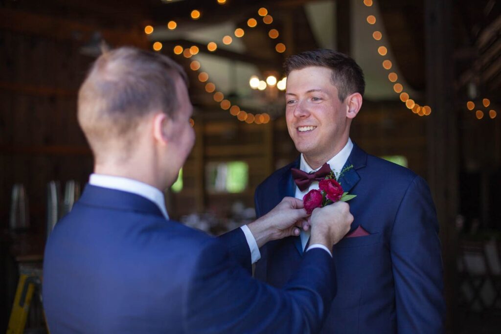 Best man pins boutonniere onto groom.