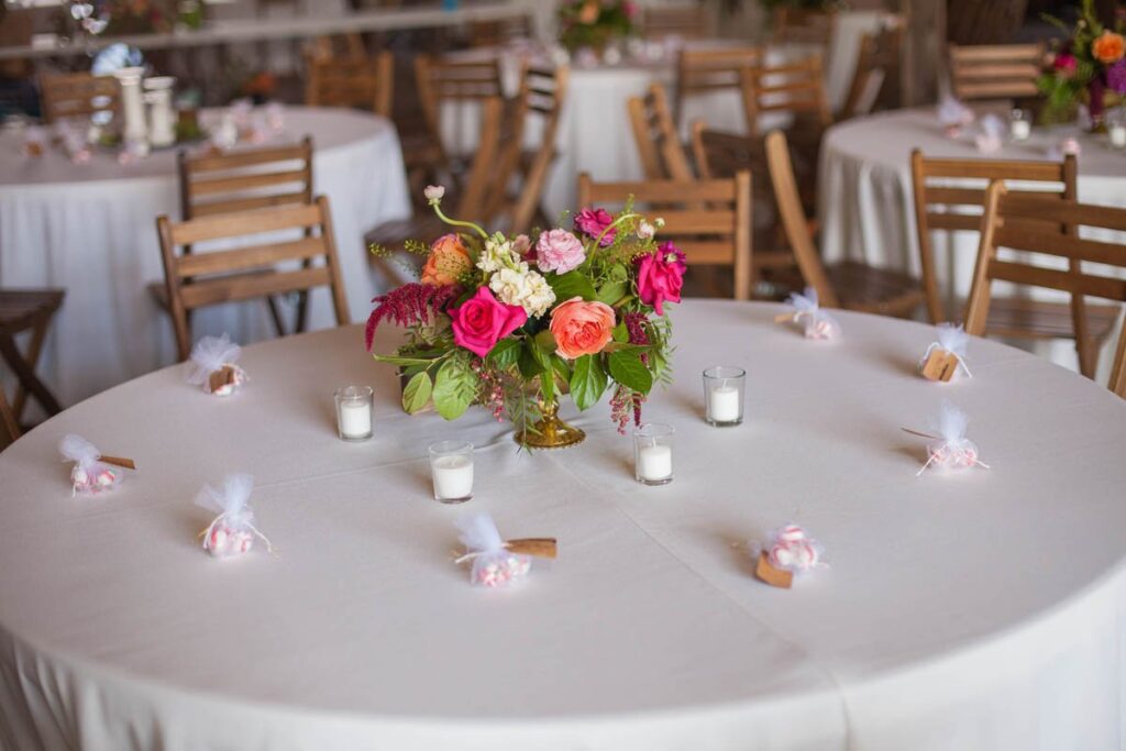 Table is decorated with mints, candles, and vibrant floral arrangement on white tablecloth.
