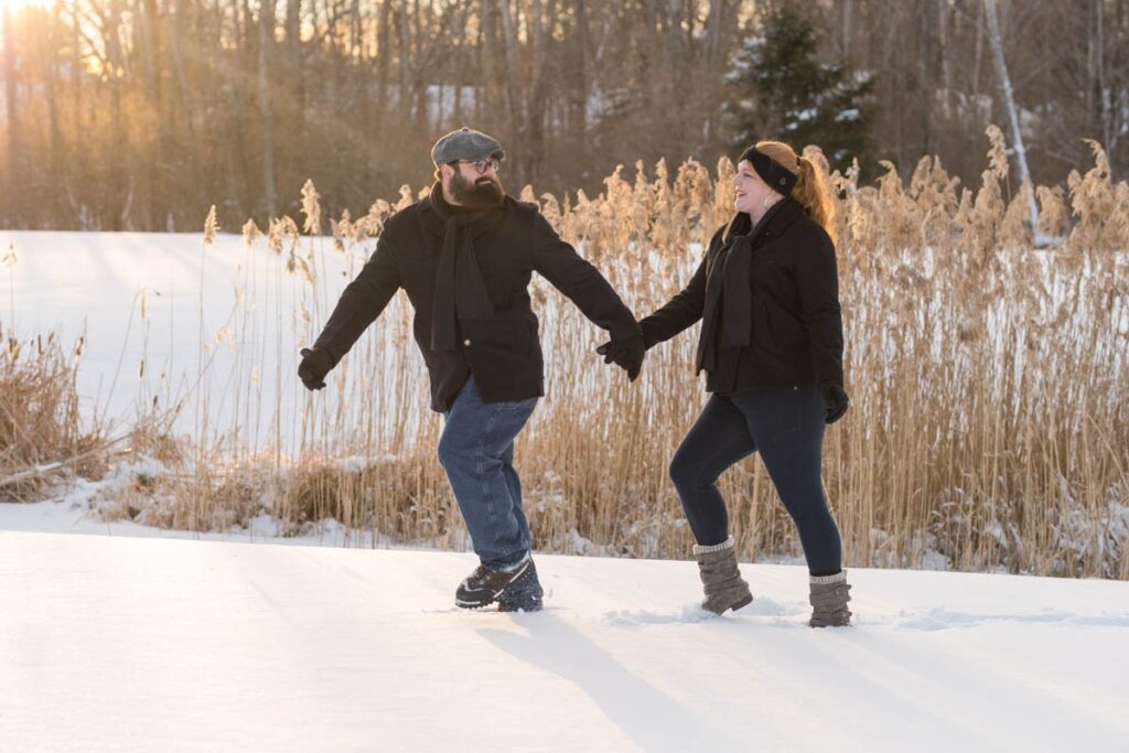 Husband and wife walk together during their photoshoot in the snow.