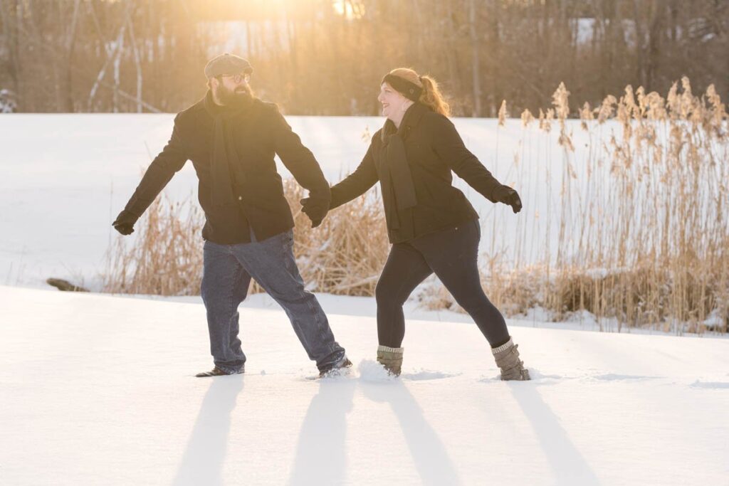 Woman and man walk together at sunset on a snowy day.