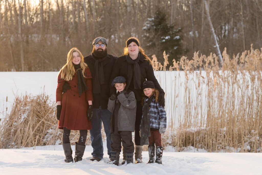 Family stands smiling together on a snowy day.