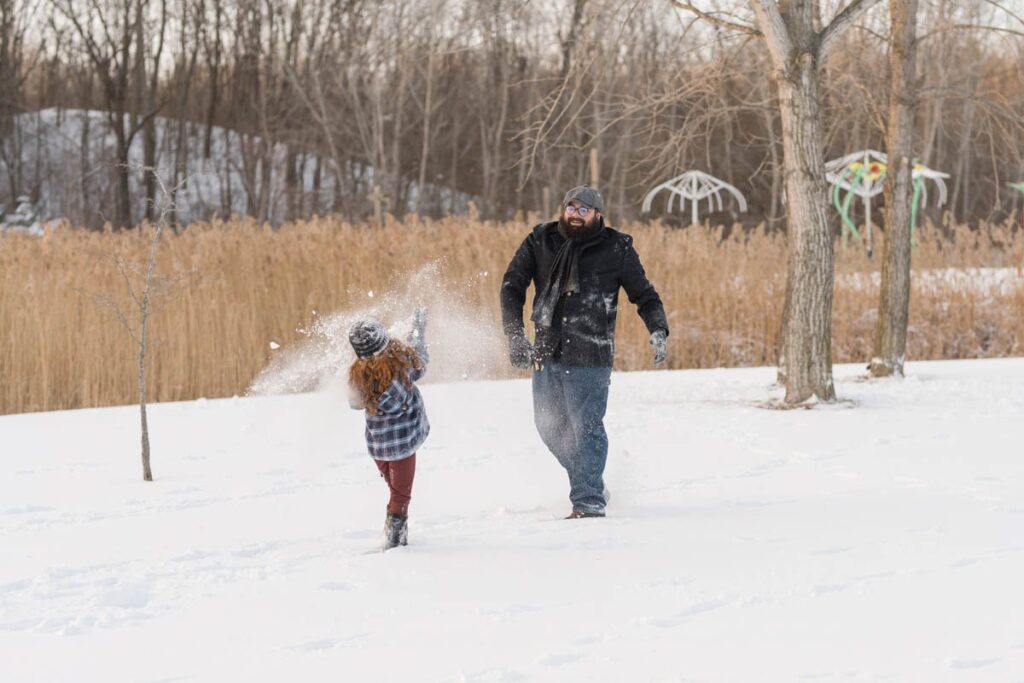 Family has fun while tossing snow at one another.