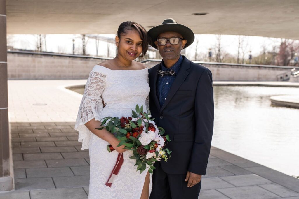 Bride smiles with her father for a portrait.