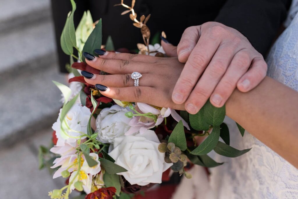 Bride and groom's hands rest on bride's bouquet at their Indianapolis elopement.