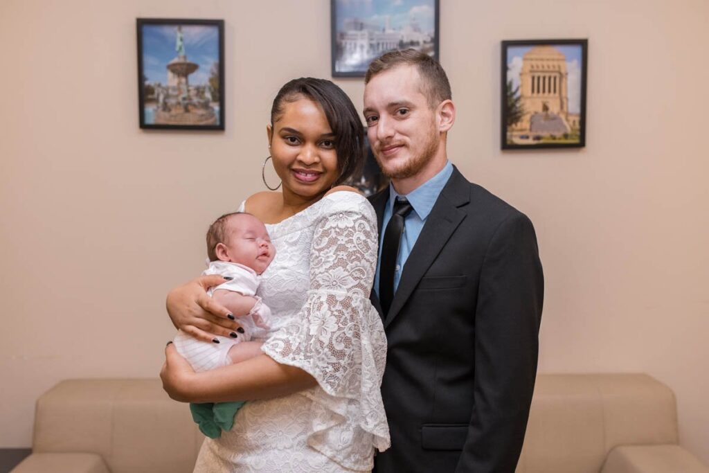Bride and groom hold their baby daughter on their wedding day.