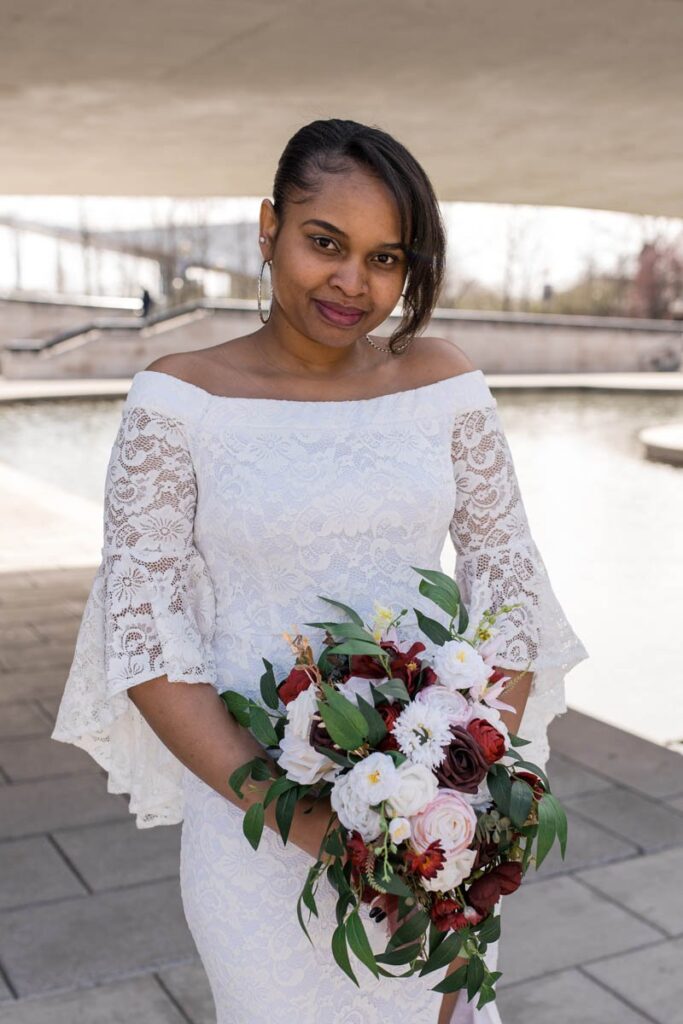 Bride holds bouquet and softly smiles.