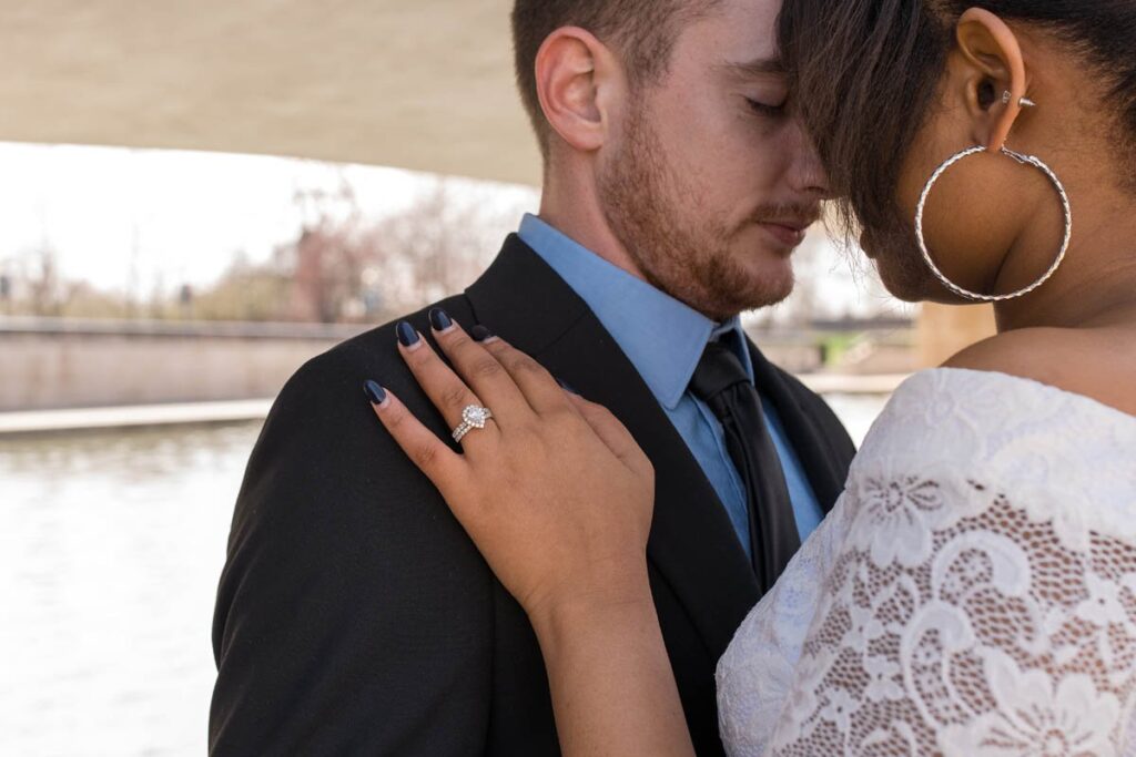 Bride and groom rest their foreheads together with closed eyes and focus is on bride's ring with her hand on groom's shoulder.