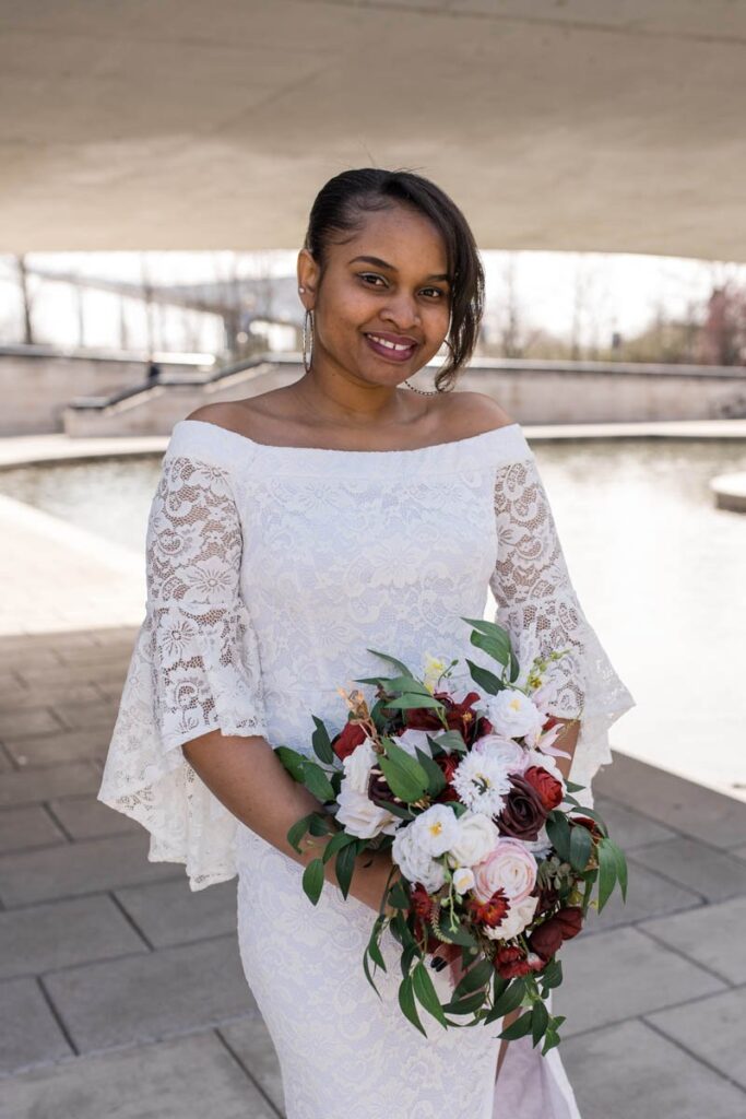 Bride holds bouquet and smiles for a portrait.