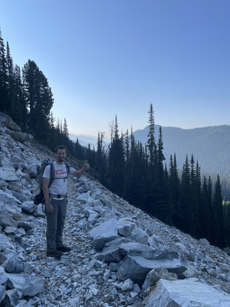 Sunrise hiker on rocky mountain trail giving a thumbs up.