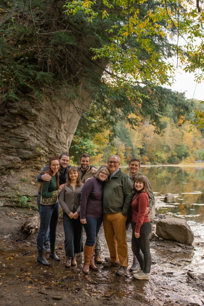 Entire family smiles together near a creek at the end of a hike through Shades State park.