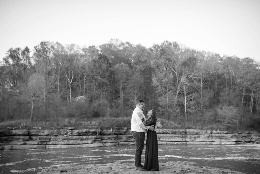 Proposal photographer photographs couple dancing together on a rock that looks out over the water at Cataract Falls State Park.