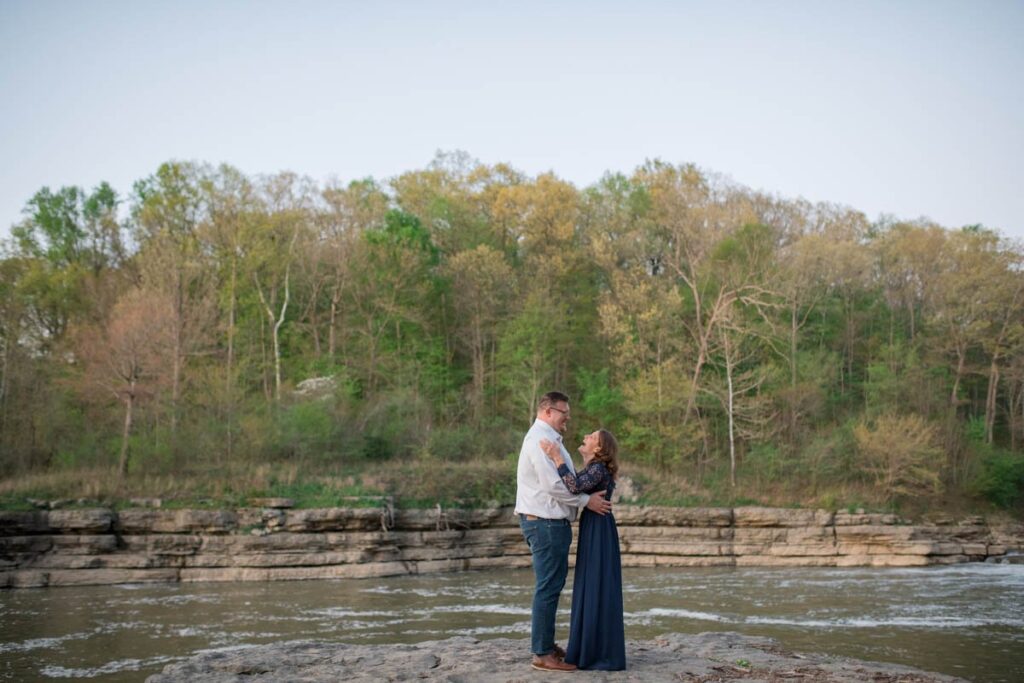 Couple laughs and dances together on a rock that looks out over the water at Cataract Falls State Park.