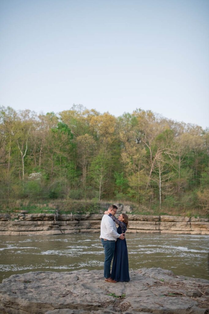 Couple slow dances on a large rock looking over the water.