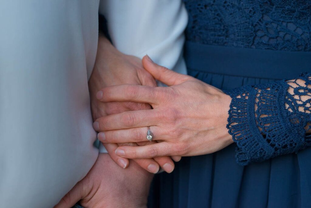 Focus on engagement ring and couple's hands.