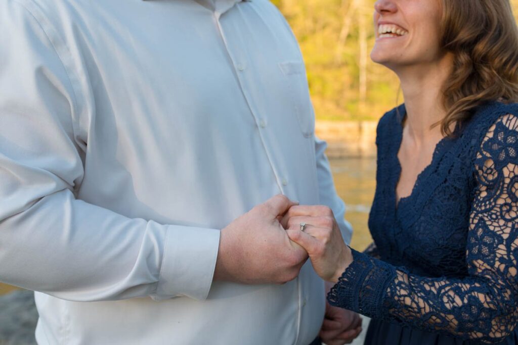 Engagement ring on woman's hand while she smiles at man.