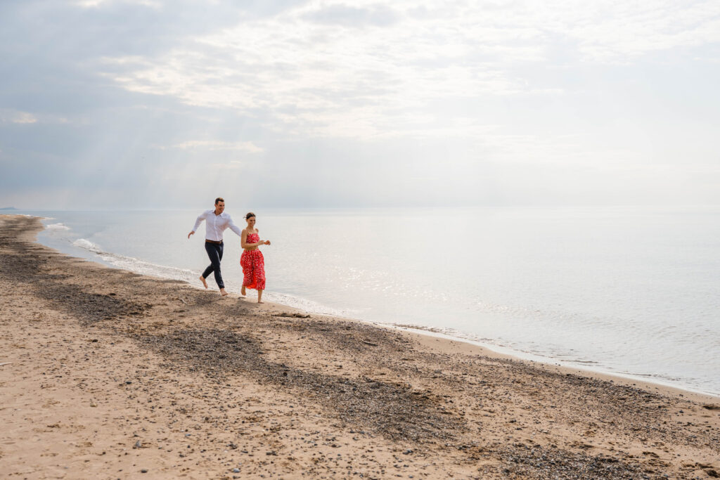 Proposal photographer captures man playfully chasing woman on the beach for engagement session.