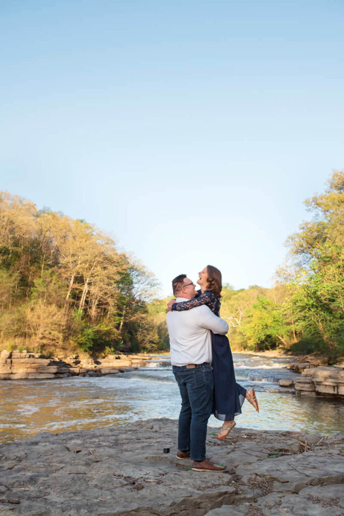 Man lifts woman up in the air while they celebrate their engagement.