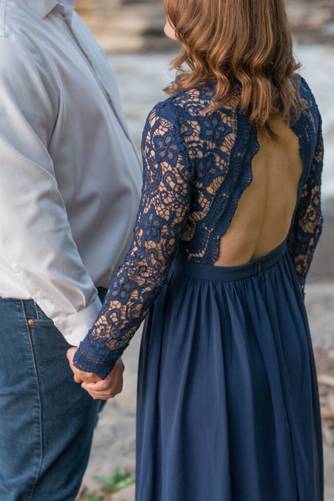 Focus is on woman's backless dress while she holds man's hand.