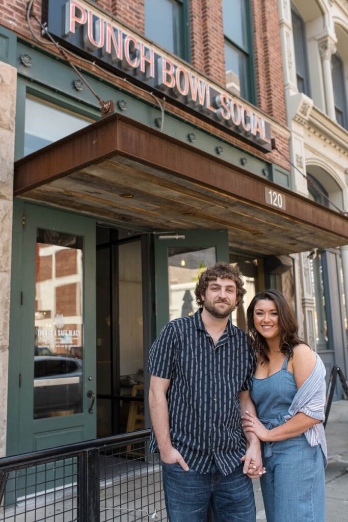 Couple smiles while standing in front of Punch Bowl Social in Indianapolis.