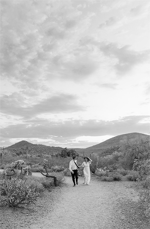 Black and white GIF of couple running through the desert holding hands.