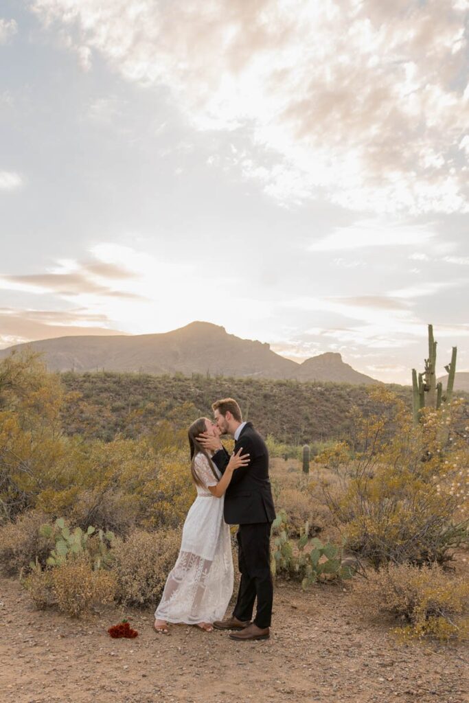 Bride and groom share their first kiss in the desert at sunset while eloping in Arizona.