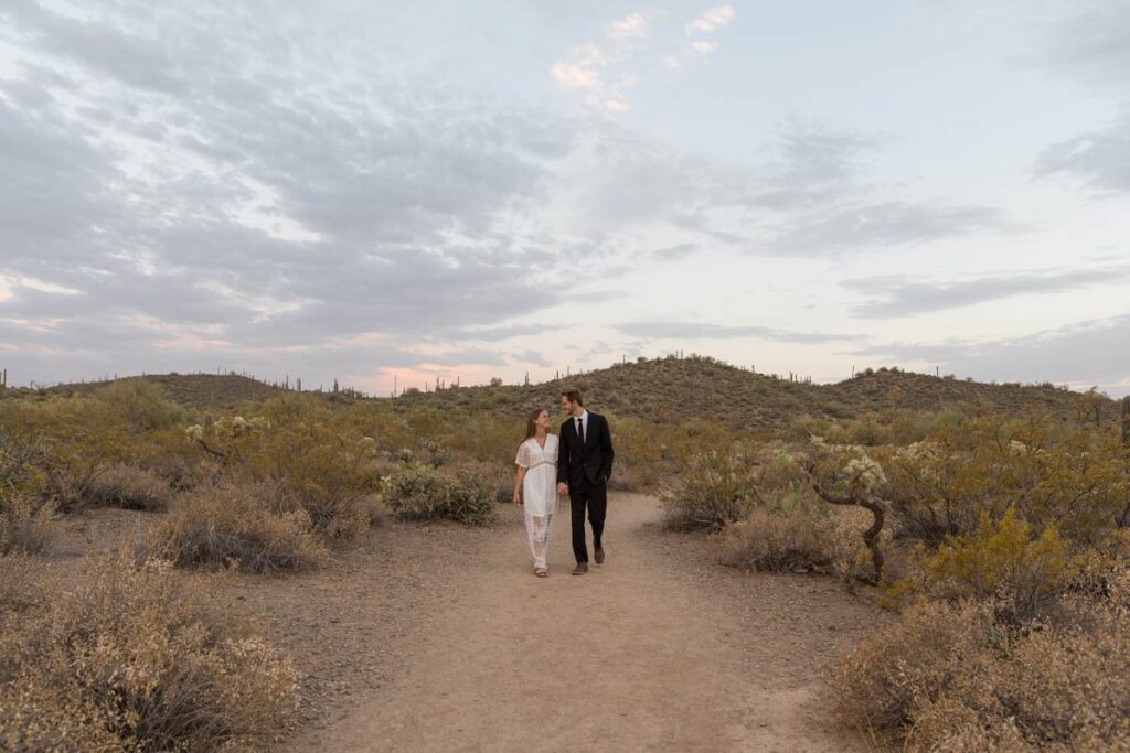 Bride and groom walk together in the desert after eloping in Arizona.
