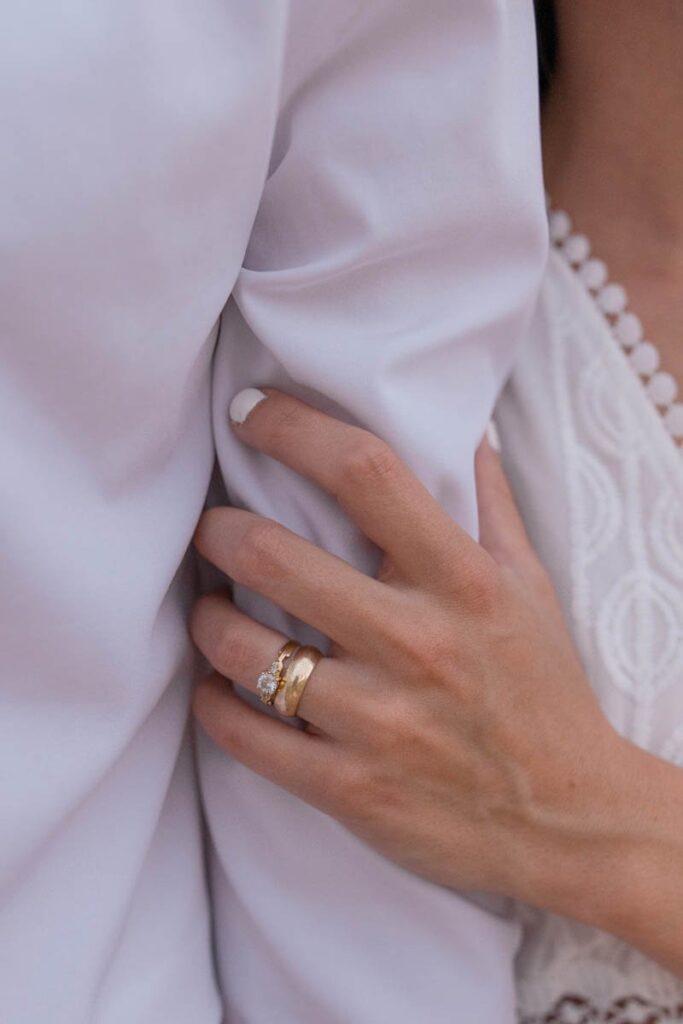 Bride's hand rests on grooms arm showing her wedding ring.