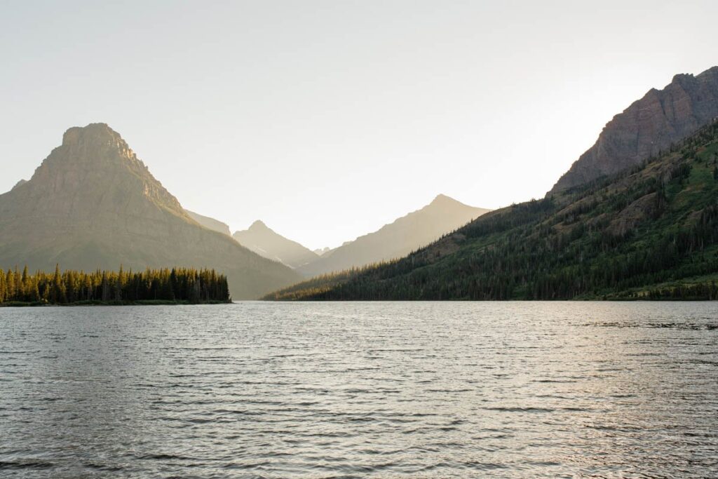 Two Medicine Lake at sunset with golden light on mountains.