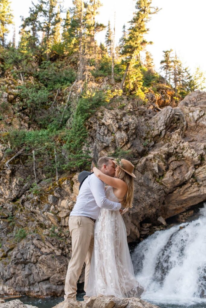 Couple kisses in front of Running Eagle Falls at Glacier National Park.