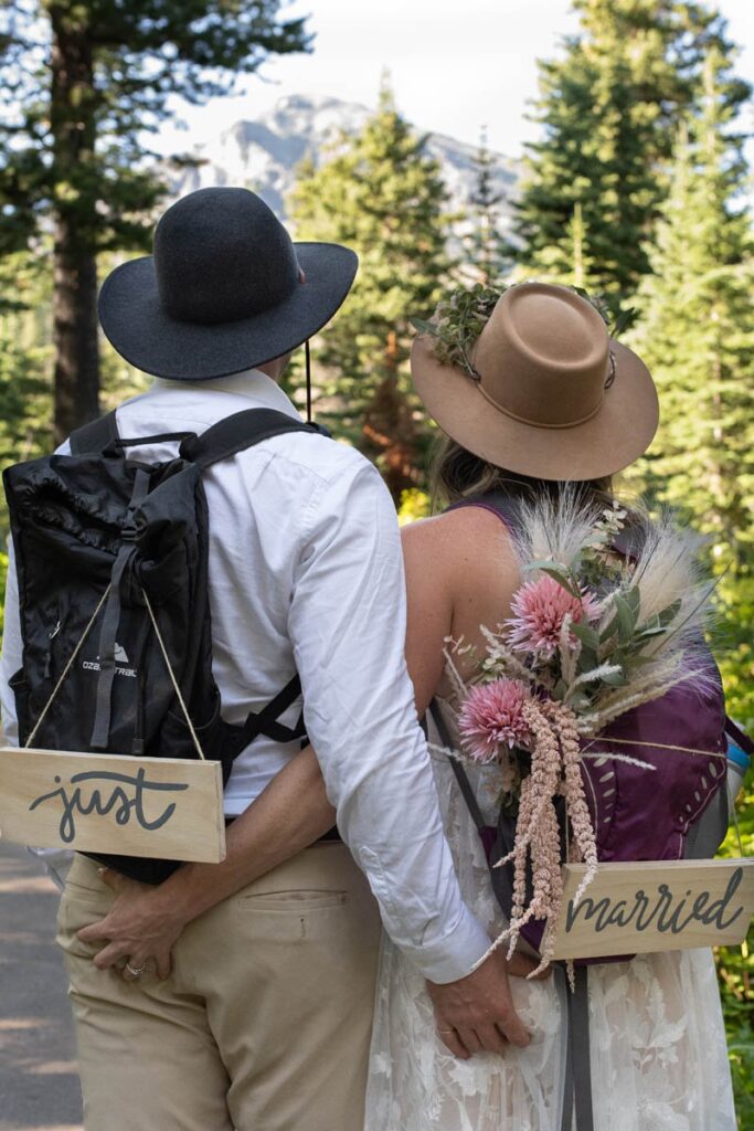 Couple admires view of mountain with "Just Married" signs on their backpacks.
