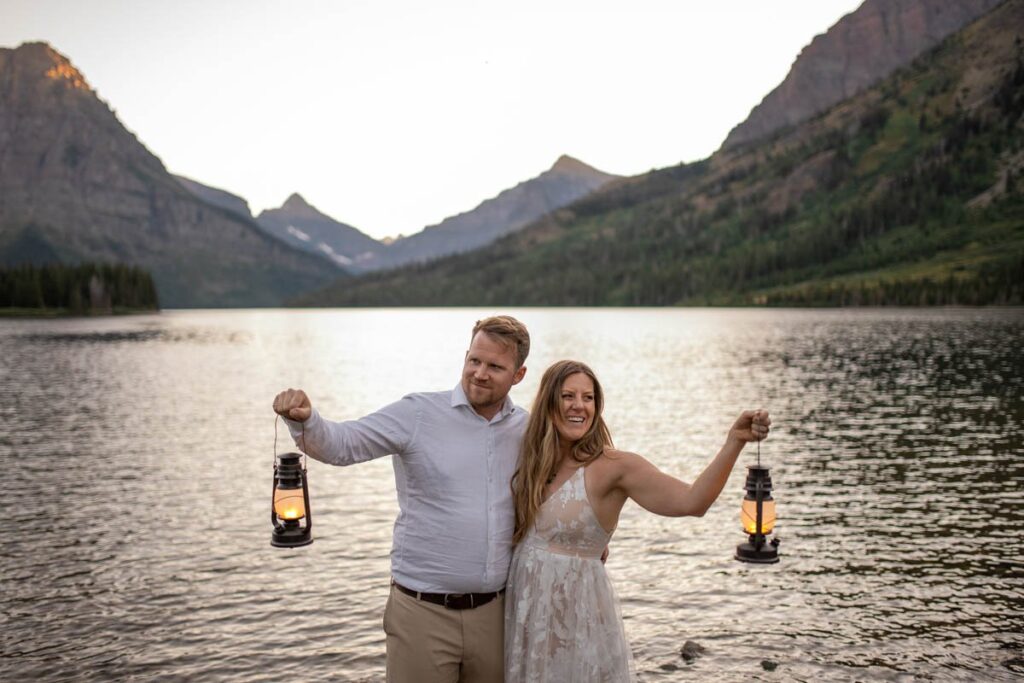 Couple holds lanterns out while standing in a lake for Glacier National Park Elopement.