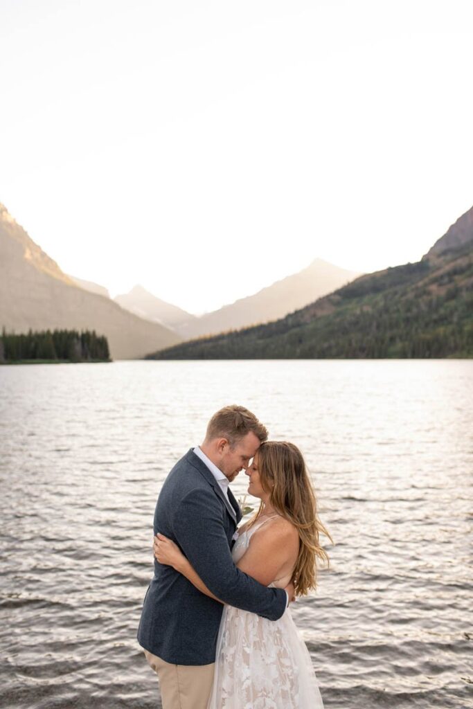 Bride and Groom hug in front of a lake at Glacier National Park.