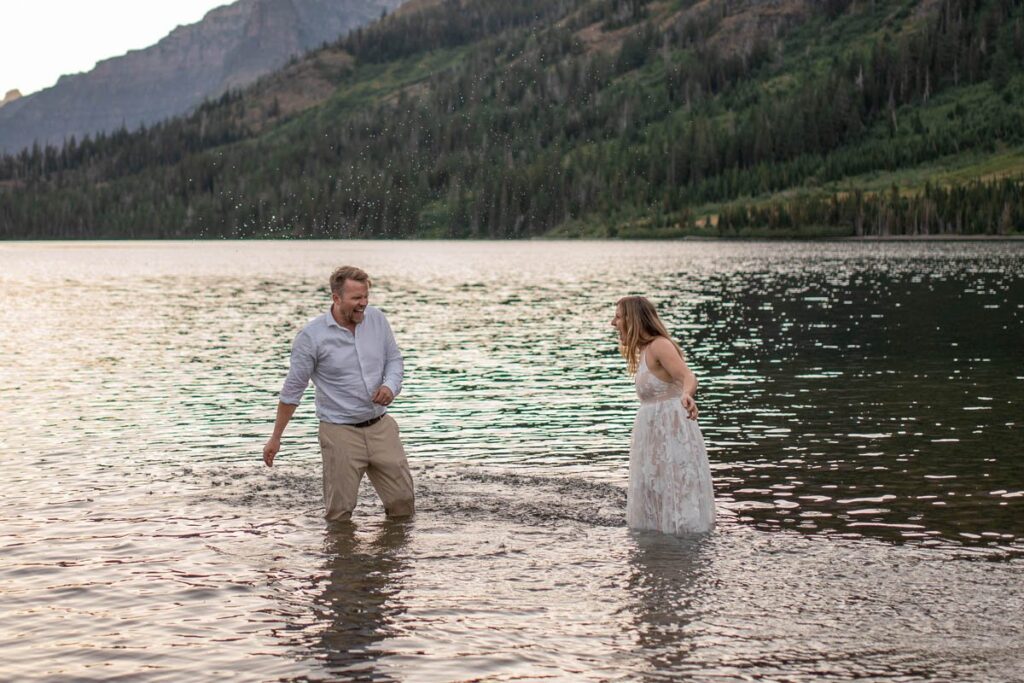Couple splashes one another in a lake in Glacier National Park.
