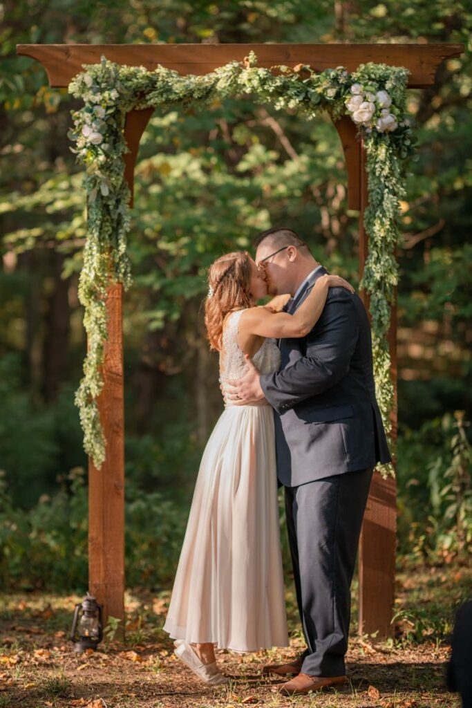 Bride stands on her tip toes to share first kiss with groom at elopement ceremony.