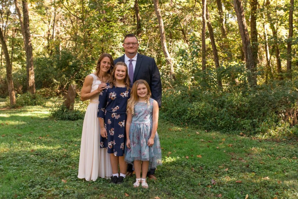 Bride and groom smiling with daughters before elopement ceremony.