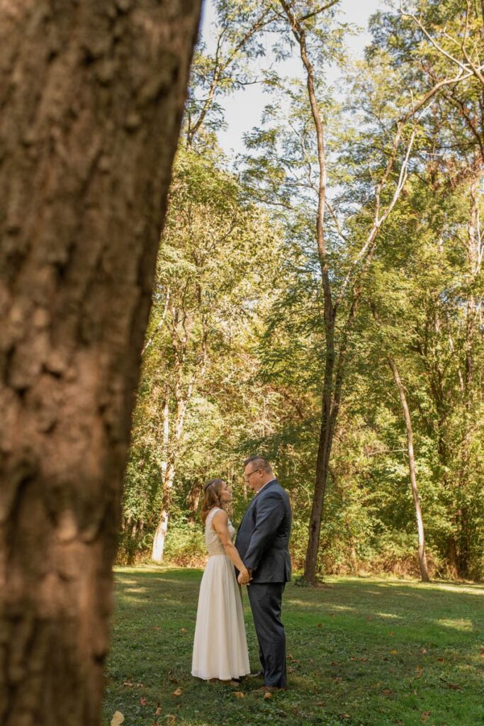 Bride and groom share a quiet moment holding hands under the trees after their first look.