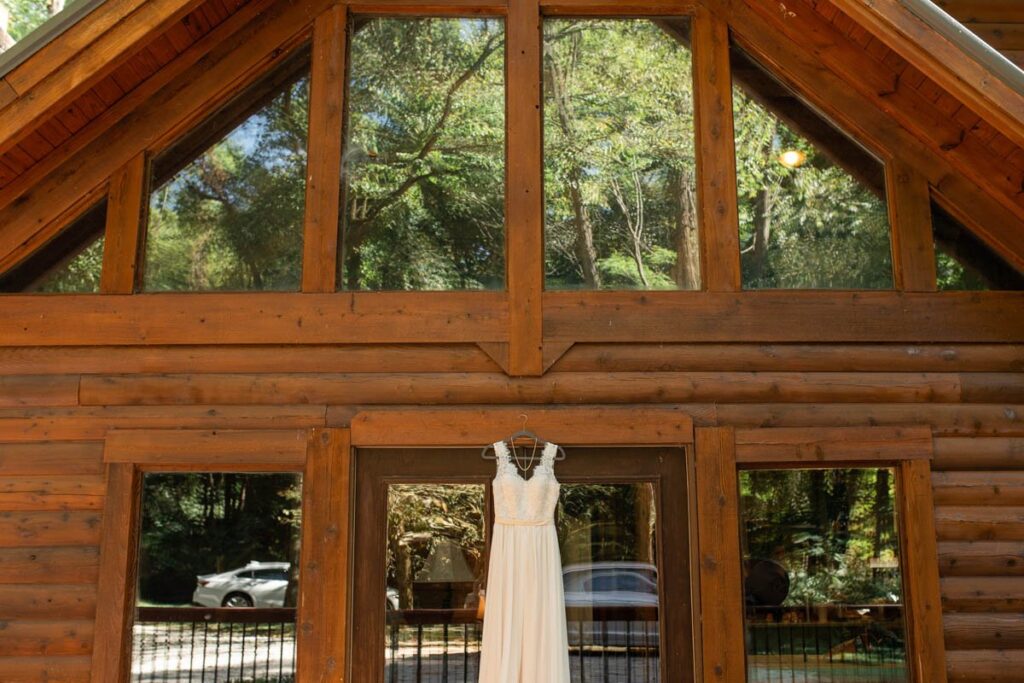 Wedding dress hangs on doorframe of a-frame cabin.