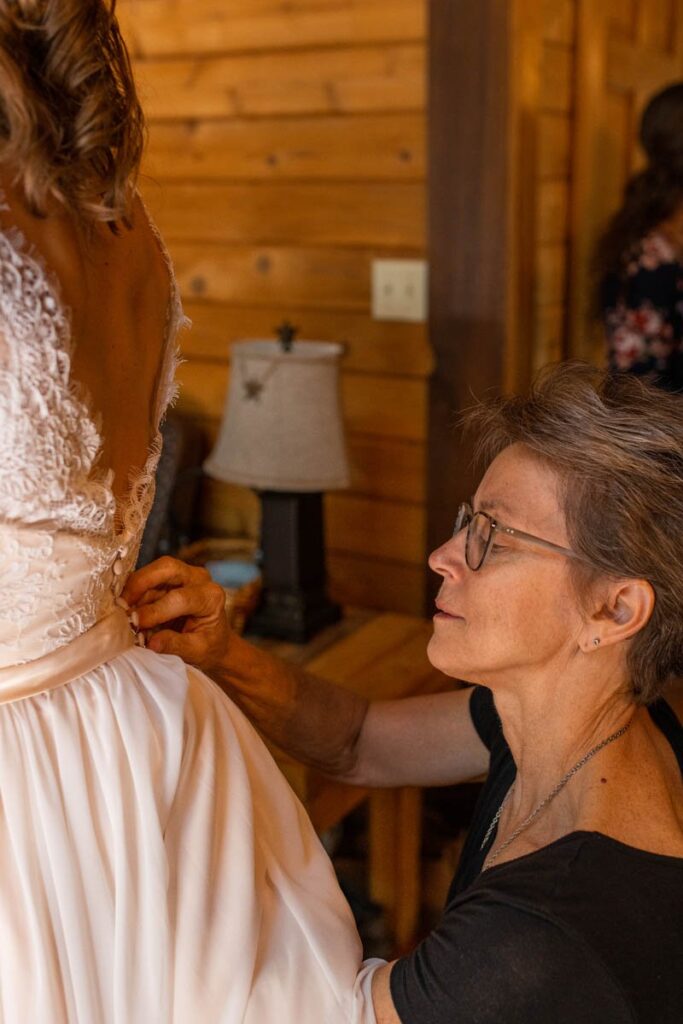Bride's mother adds a few stitches on the back of her wedding dress.