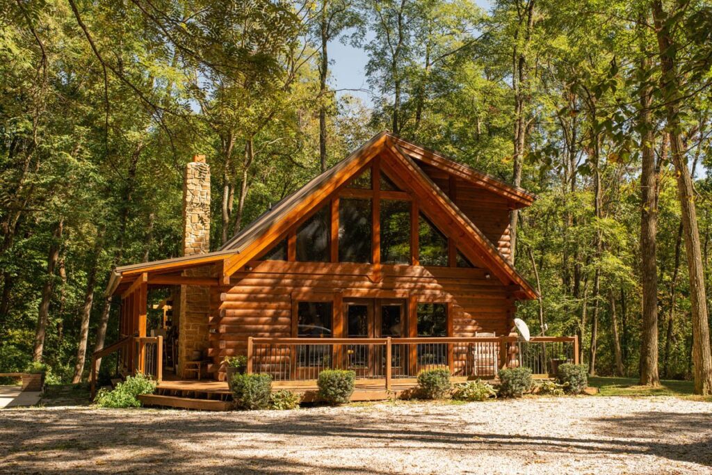 Log cabin sits nestled among trees on a sunny day at Sugar Creek Retreat.